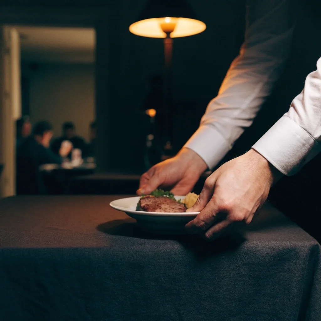 Nakryty stół w restauracji, talerz w trakcie kolacji, ciepłe światło lampy